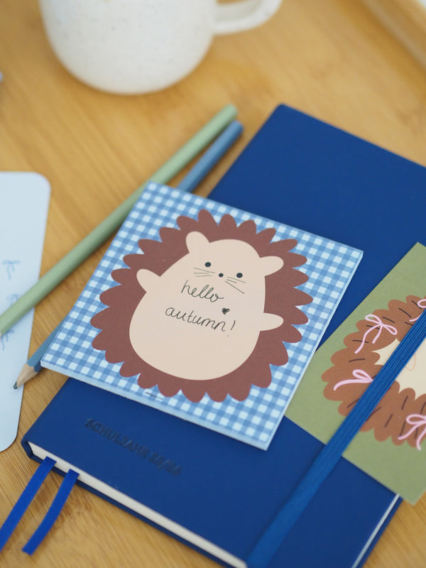 Notizblock Igel mit Aufschrift hello autumn auf blauem Notizbuch