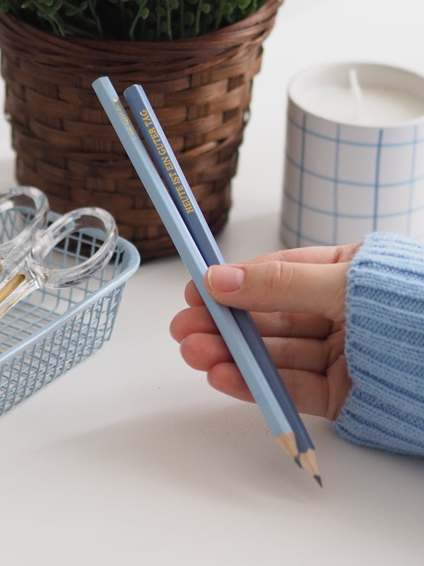 Bleistifte in Blau in der Hand am Schreibtisch