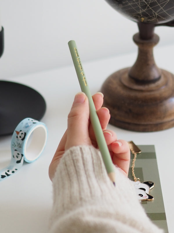 Bleistift in Khaki in der Hand am Schreibtisch